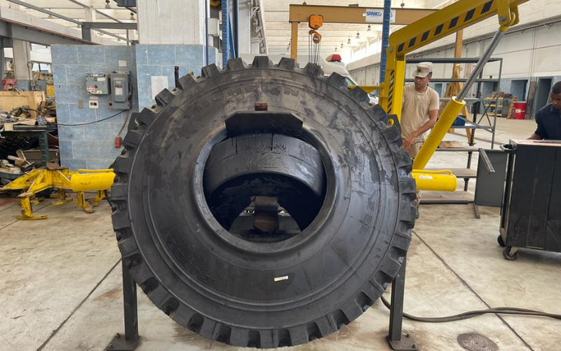 Heavy-duty military run-flat tire positioned on GM Defensive maintenance equipment inside a workshop