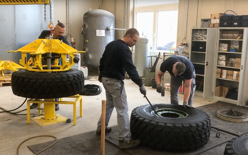 Military maintenance crew performing run-flat tire service with GM Defensive equipment in a workshop environment